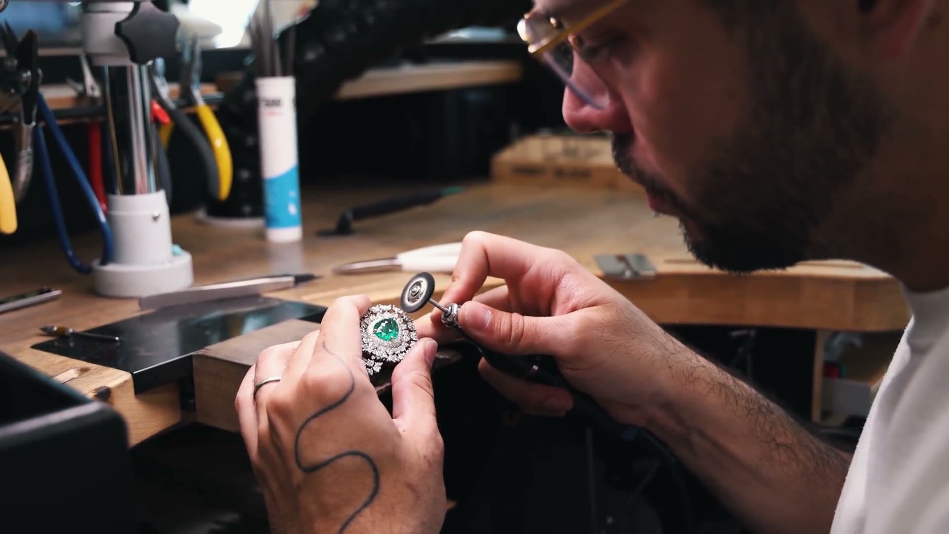 Jeweller working a gem-set piece with a polishing disc at the Geneva workbench