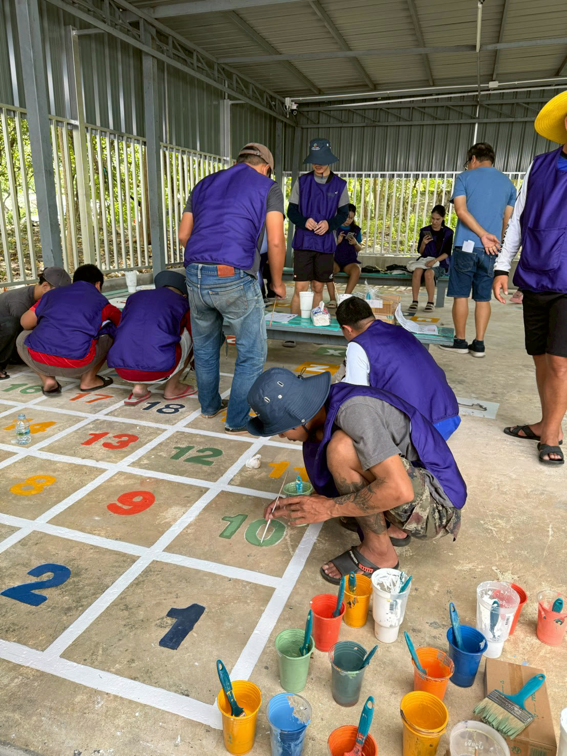 NIRU volunteers painting a numbered game on a school playground