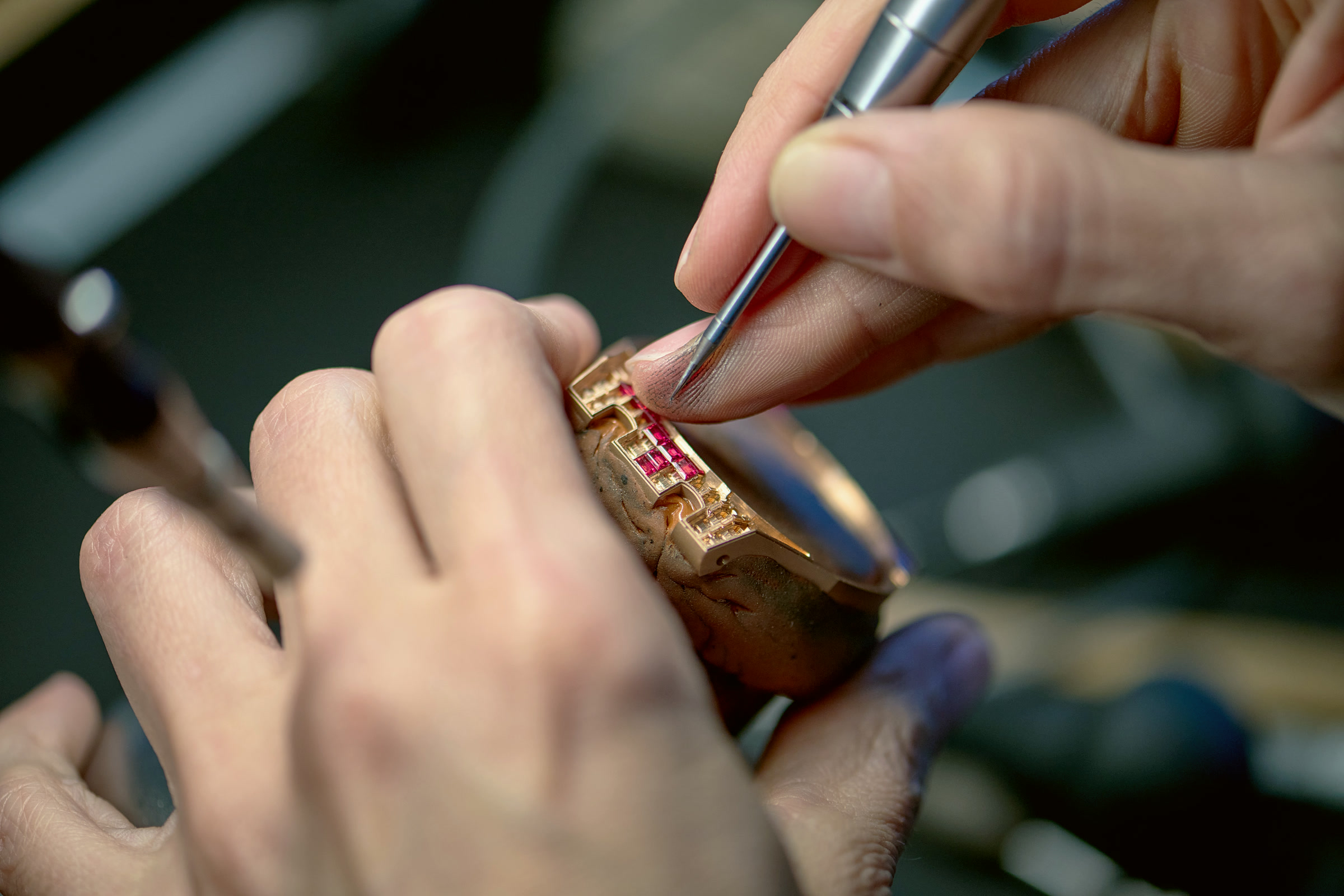 Hands setting rubies into a gold piece
