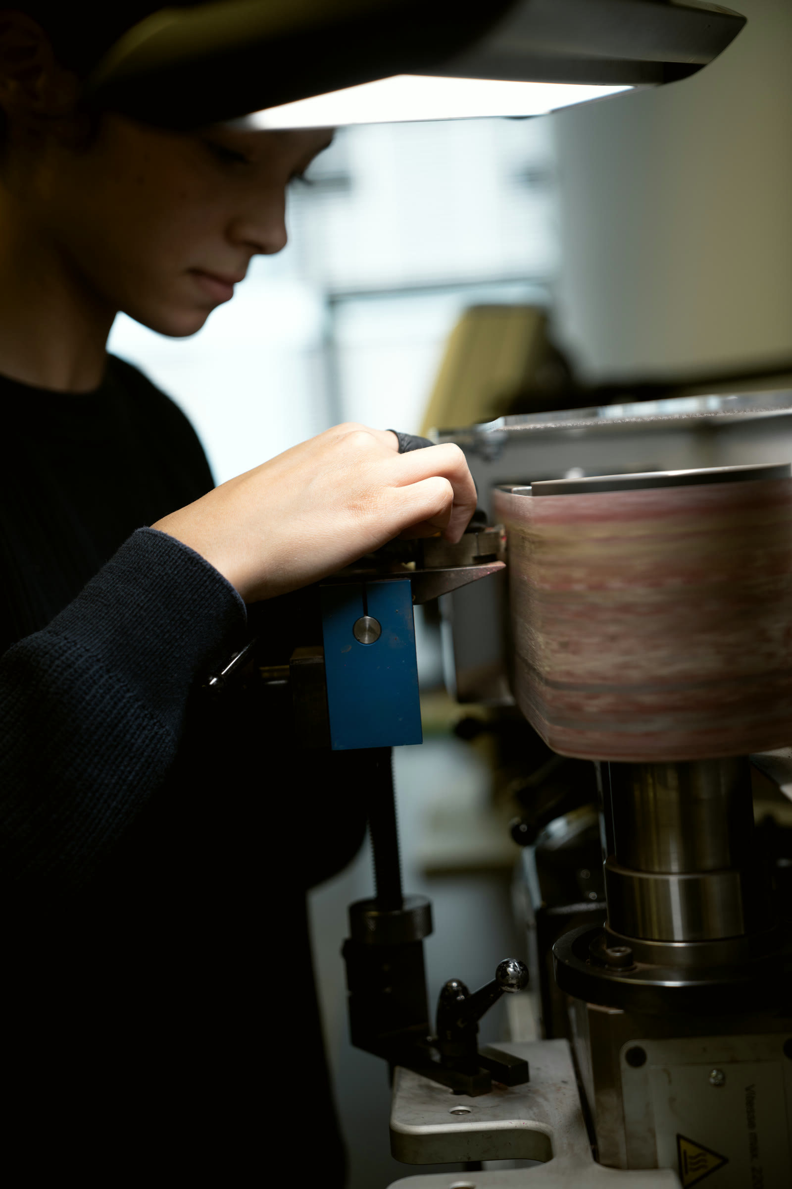 Finisher working a component at the sanding drum in the finishing workshop