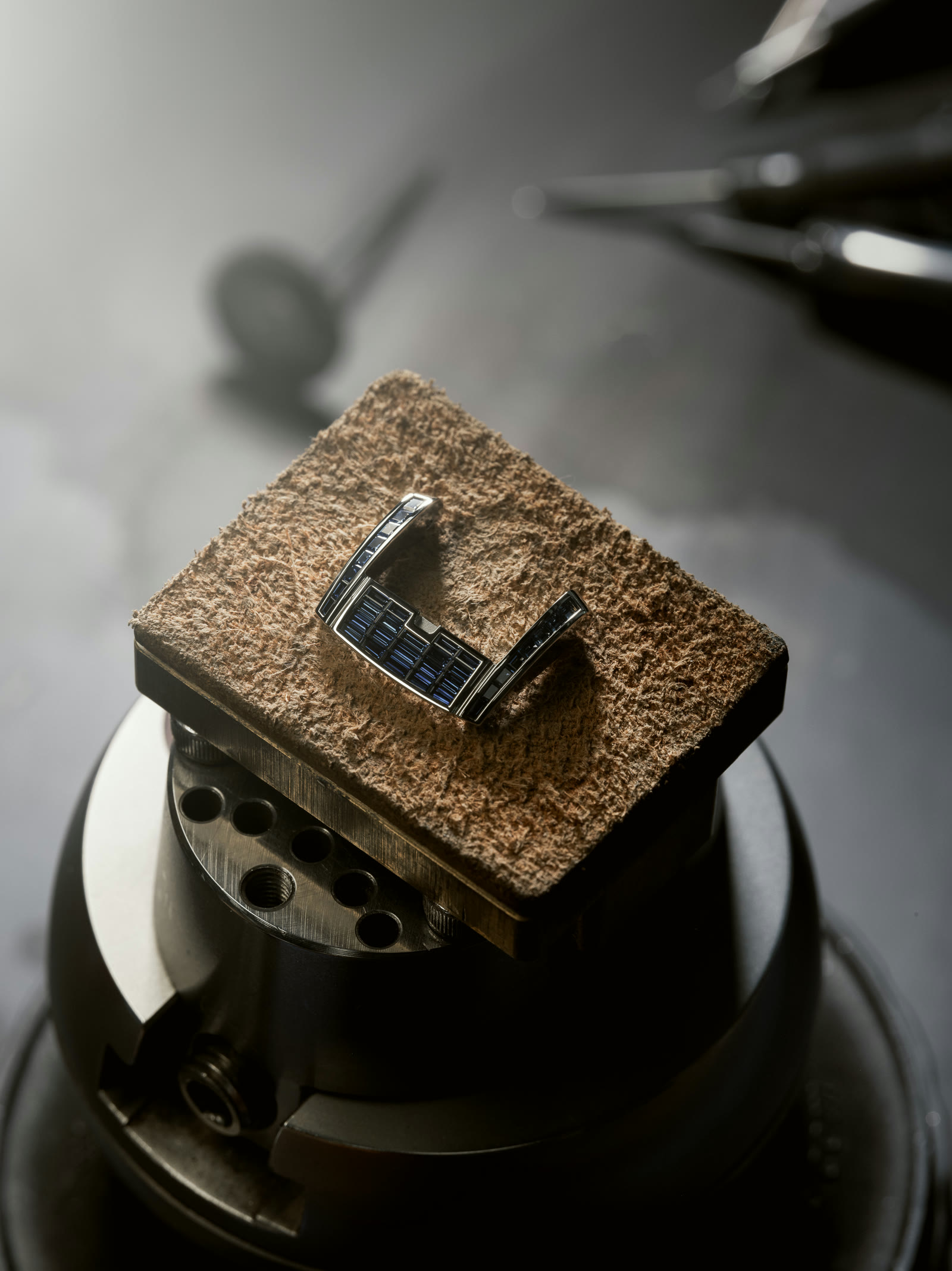 Watch component set with baguette sapphires resting on the setter's cement block