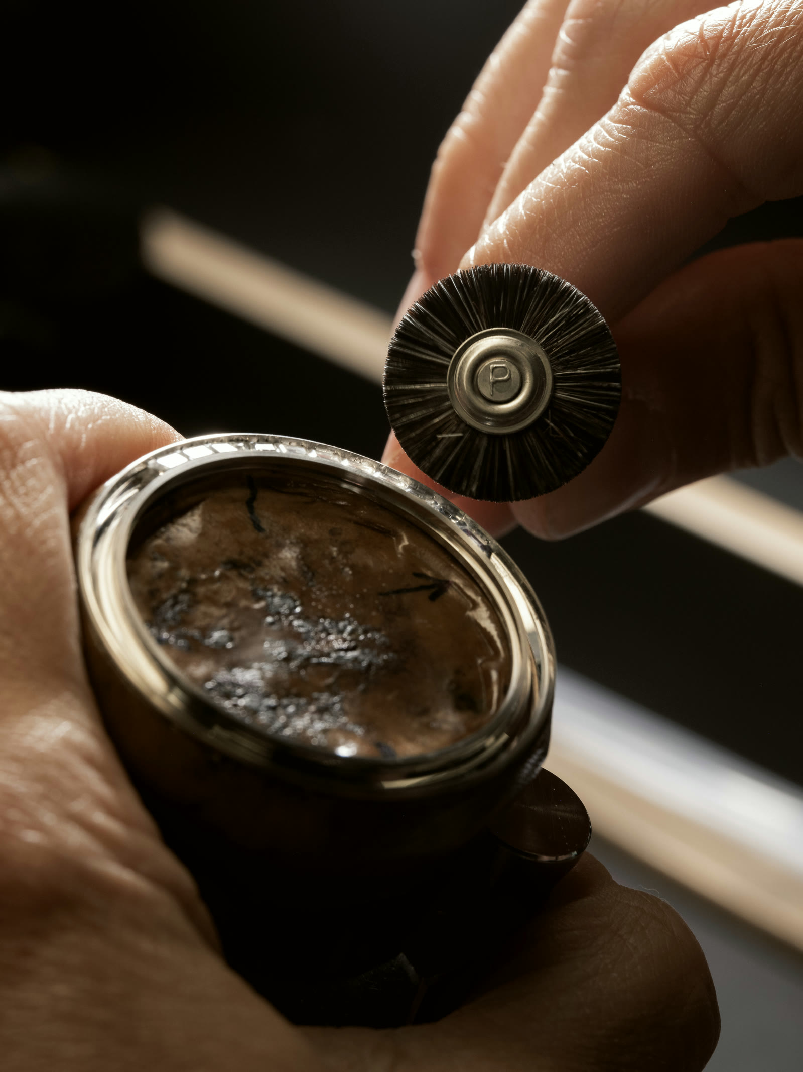 Bristle brush wheel cleaning a set watch bezel