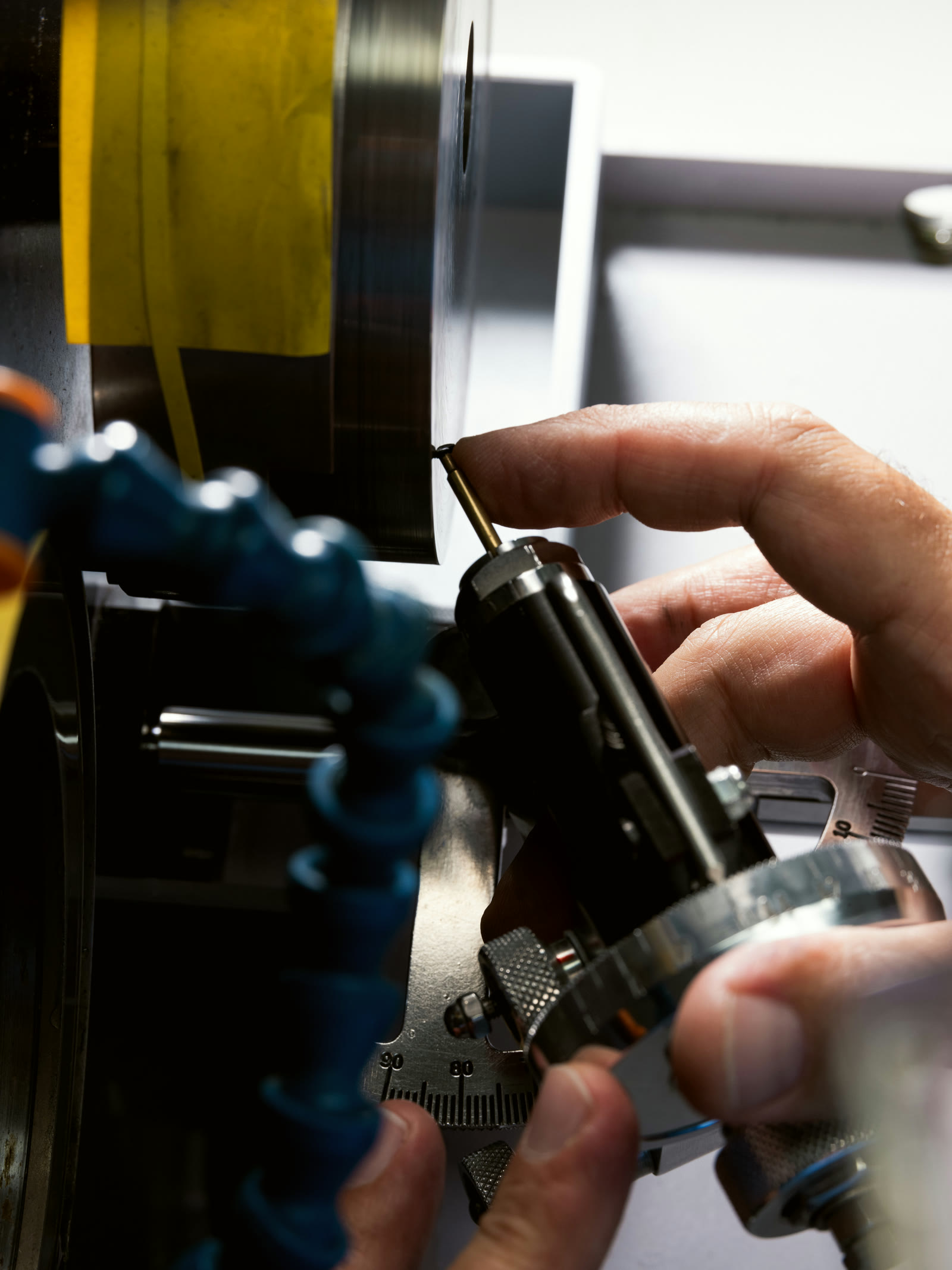 Turned watch component mounted on its holder beside the machine