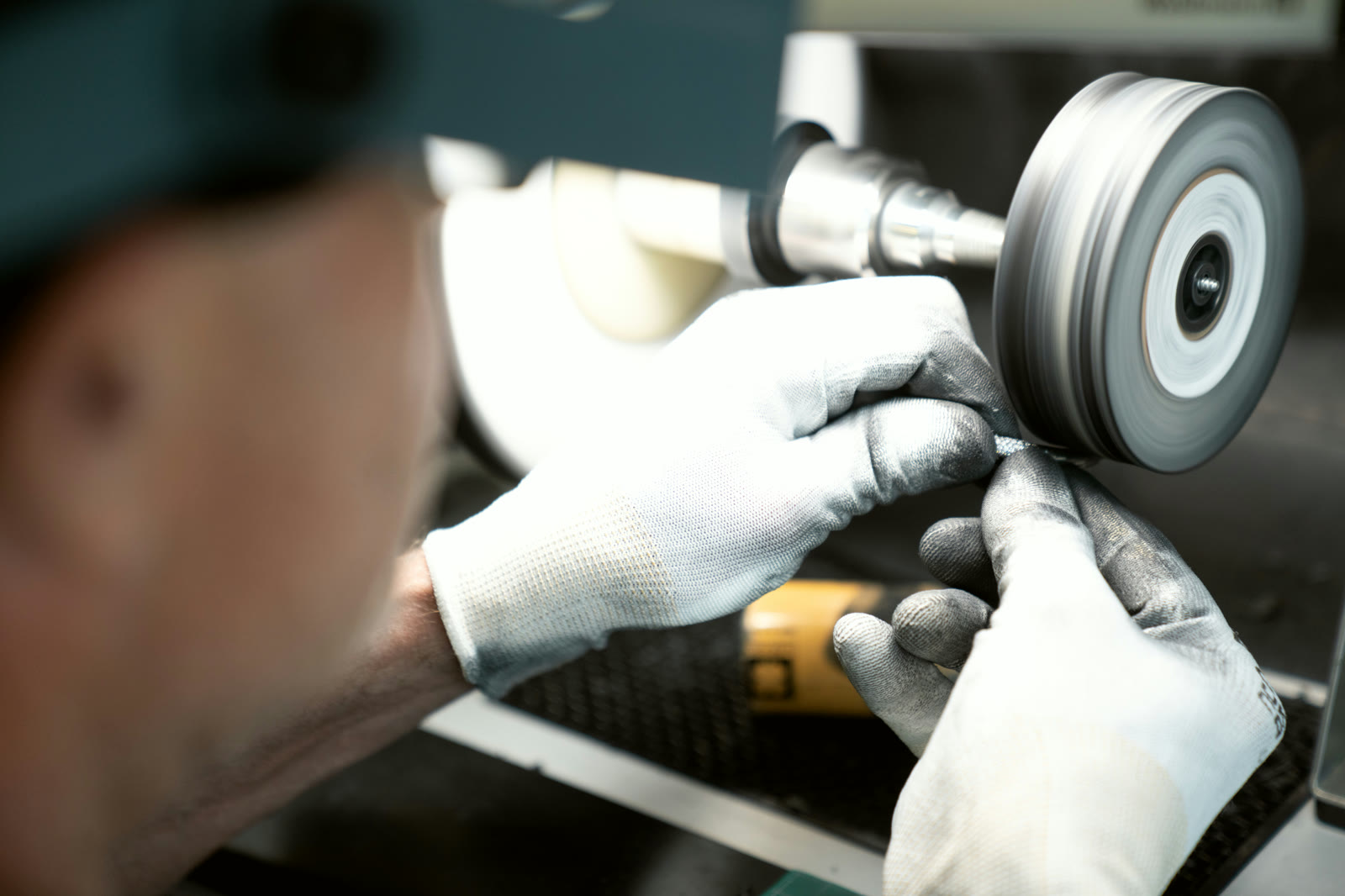 White-gloved finisher polishing a component at the wheel