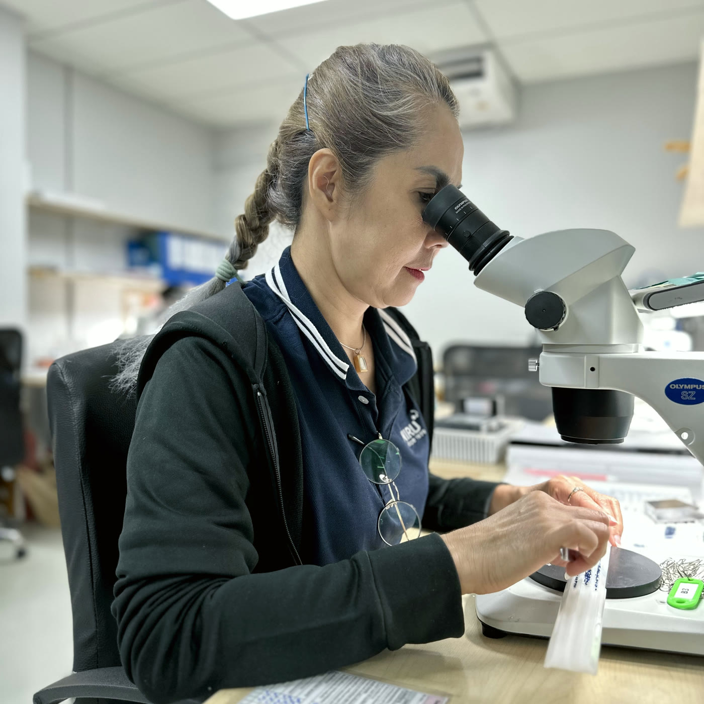 NIRU gemmologist examining a parcel of stones under a stereo microscope in an in-house screening laboratory