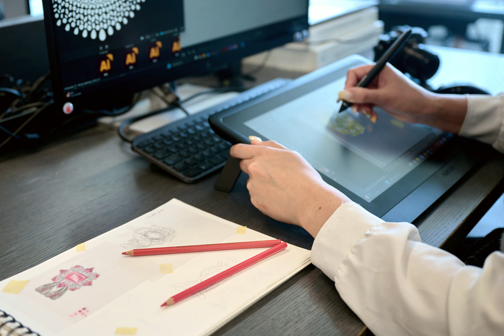 Designer's desk: pencil sketches, Wacom tablet and a reference render on screen