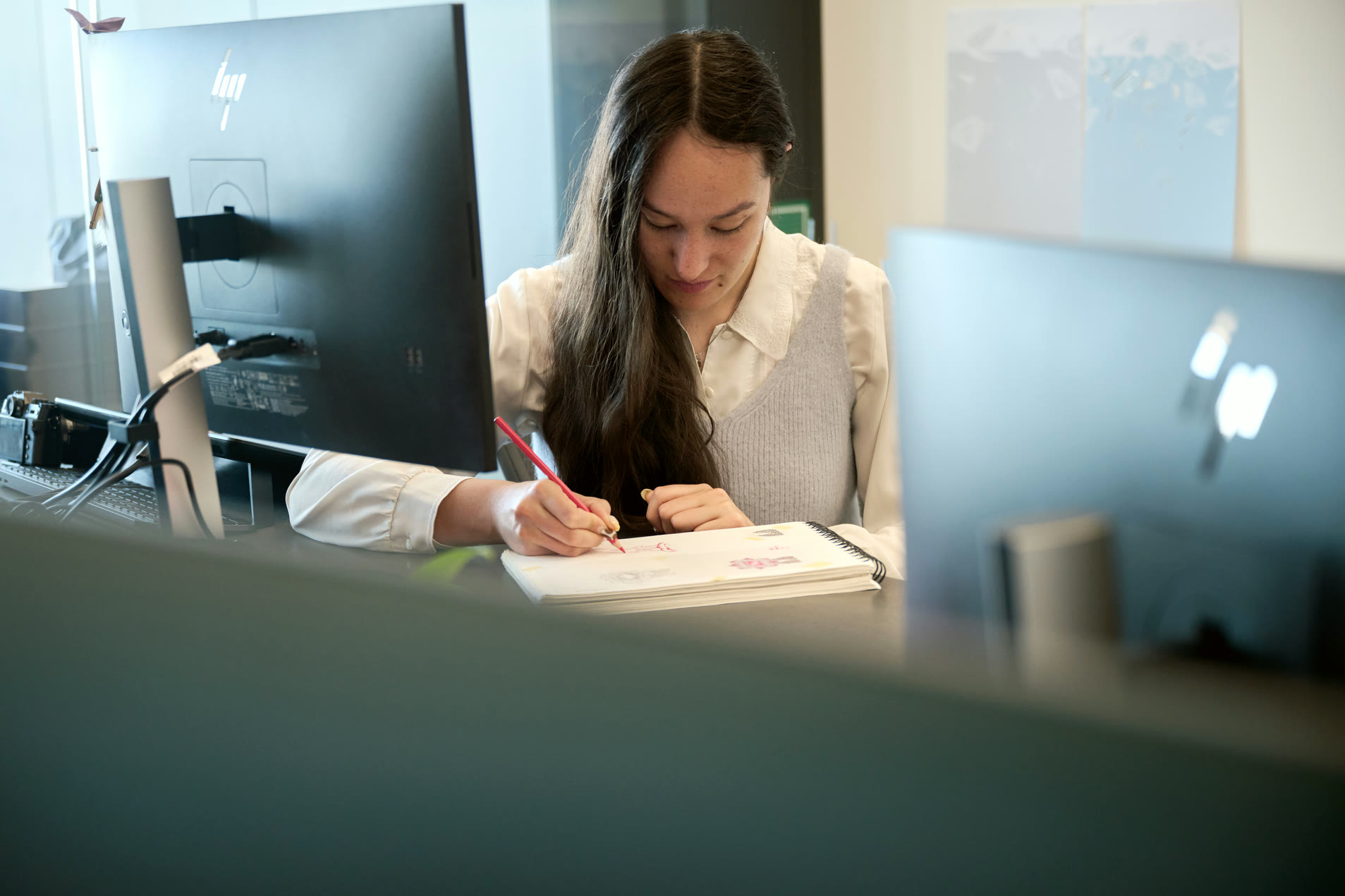 Designer sketching on a notebook between studio monitors